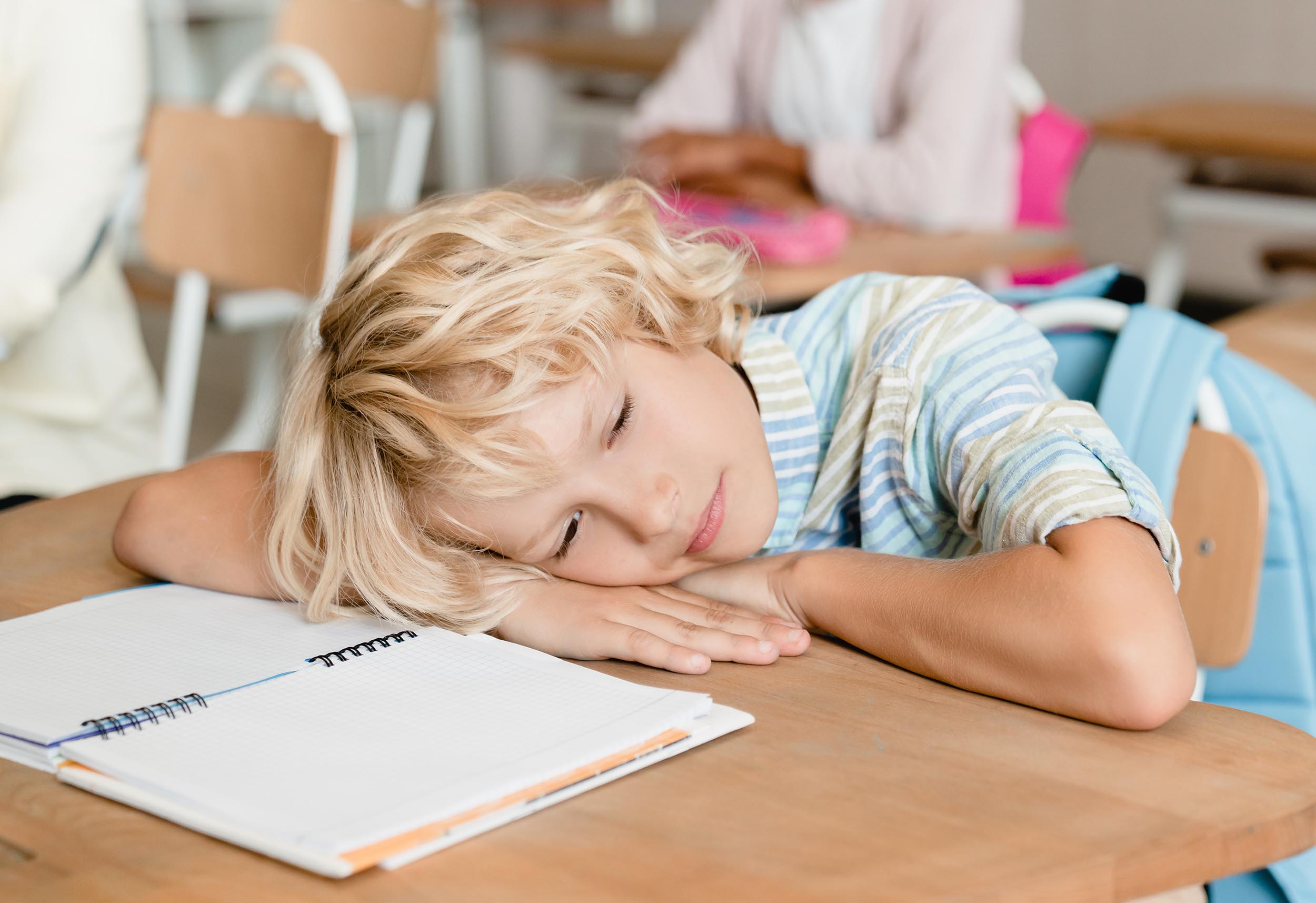 Sleepy tired bored schoolboy pupil student sleeping at the desk in school during the lesson class. F-student, flunky lazybones.