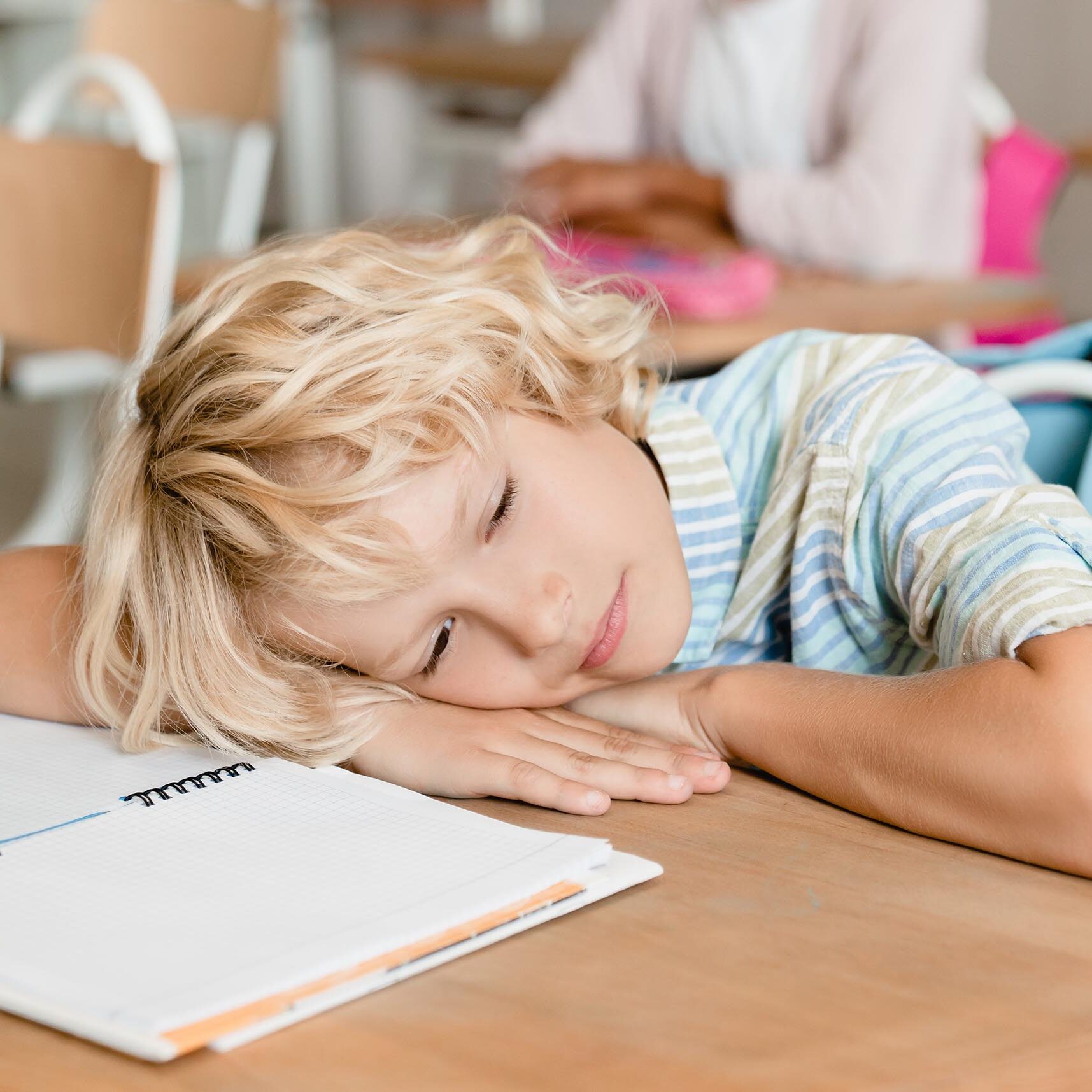 Sleepy tired bored schoolboy pupil student sleeping at the desk in school during the lesson class. F-student, flunky lazybones.